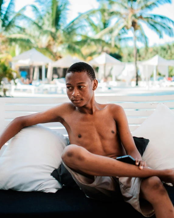a young black male sitting on a cushion with a remote