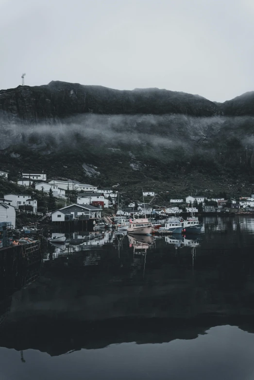 a foggy scene of a mountain village by the water