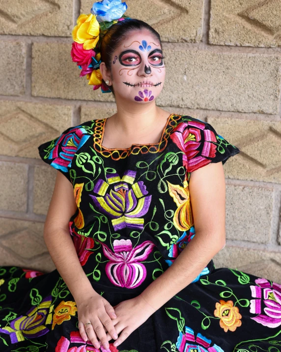 a child with colorful makeup sitting on the ground