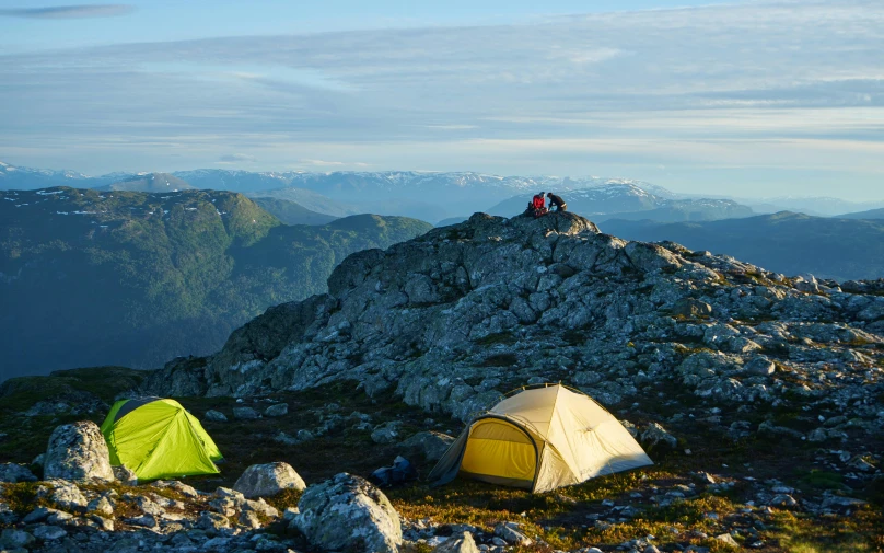 tents and people are camping on a large mountain peak