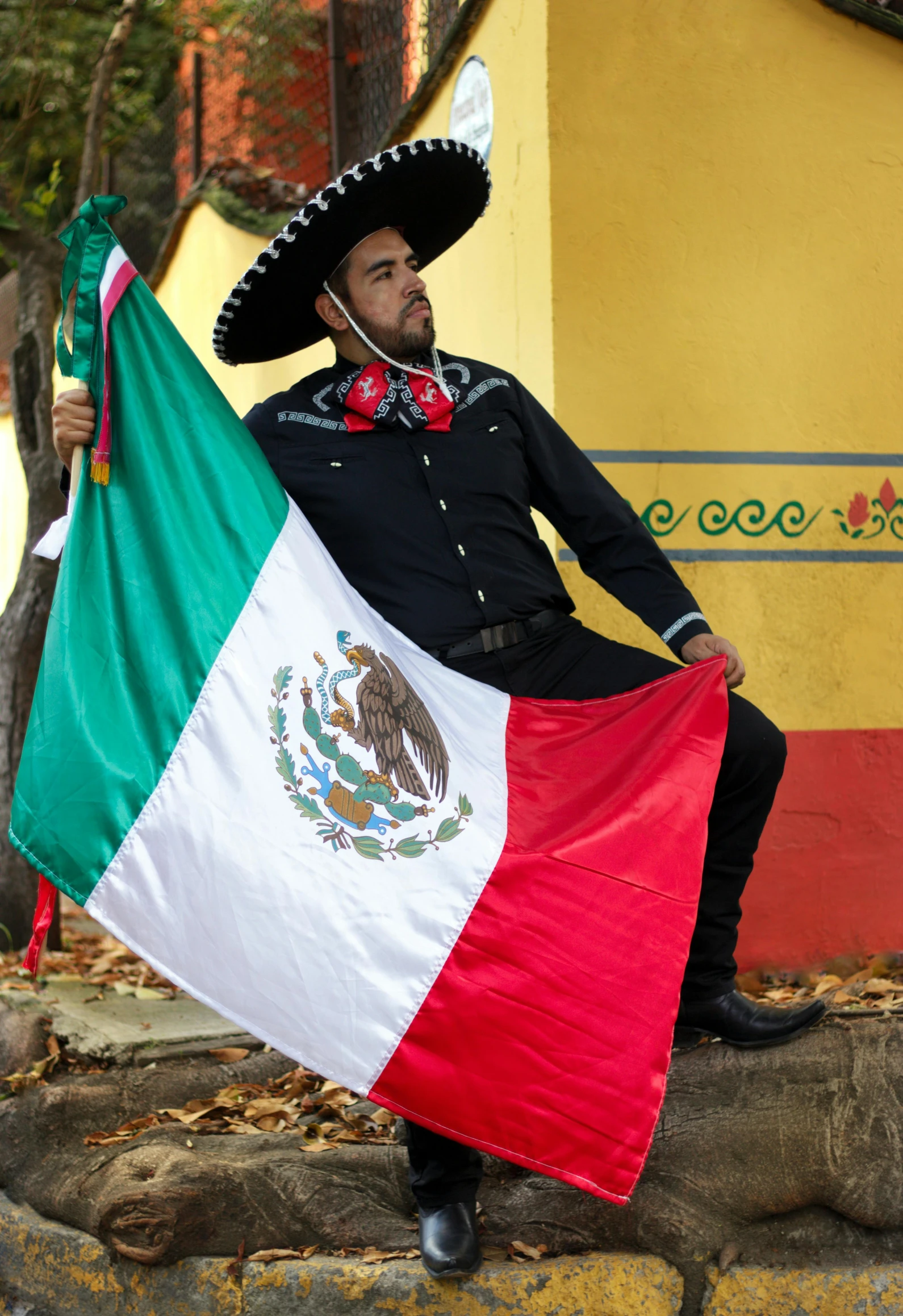 a man dressed in an old time costume holds up a mexican flag