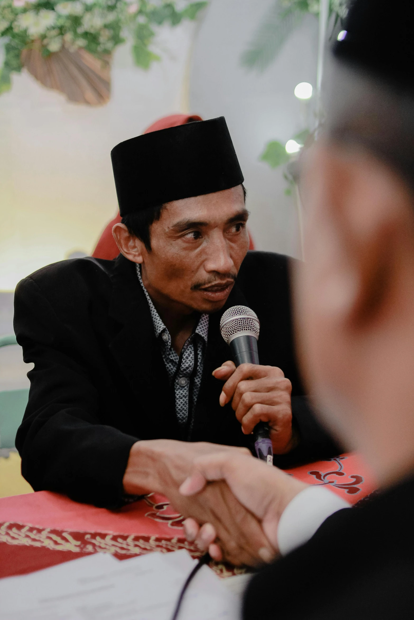 a man in a turban talks to someone at a microphone