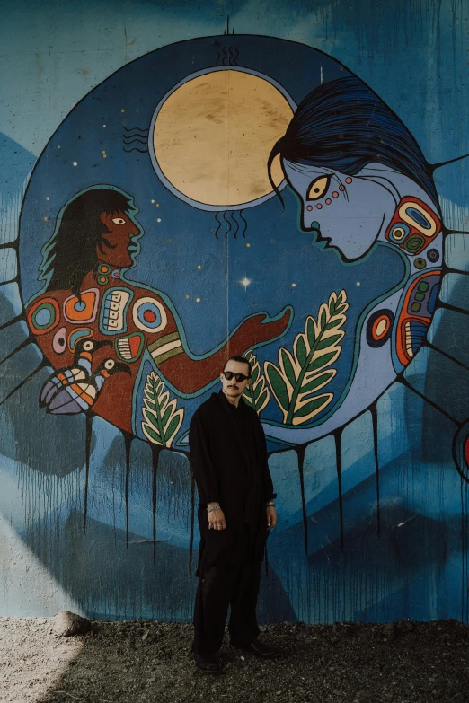 a man standing in front of an artistic wall