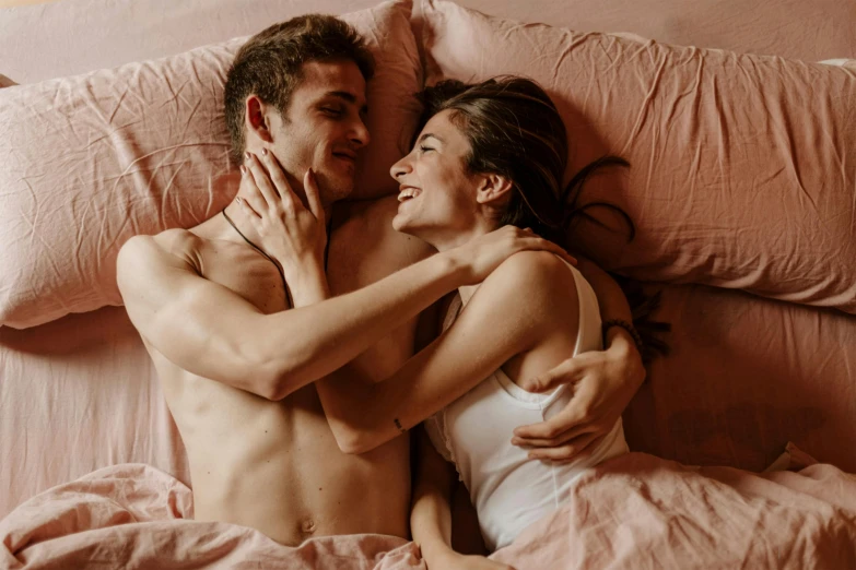 a couple laying in bed with each other under covers