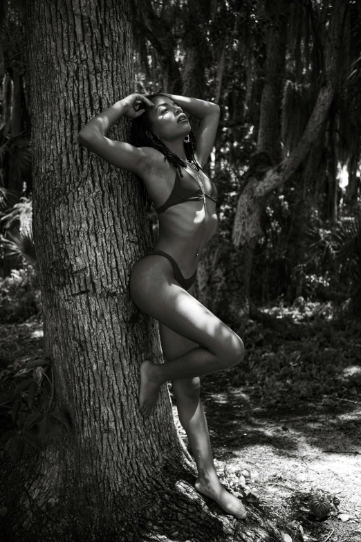 a woman posing next to a tree in a bathing suit