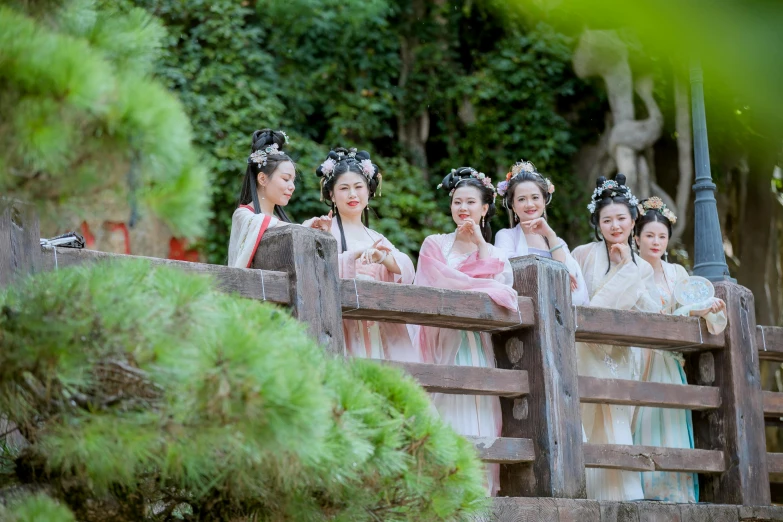 six women in traditional chinese clothing standing on a bridge