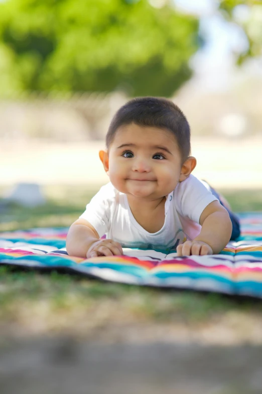 a small child smiles while lying on a blanket