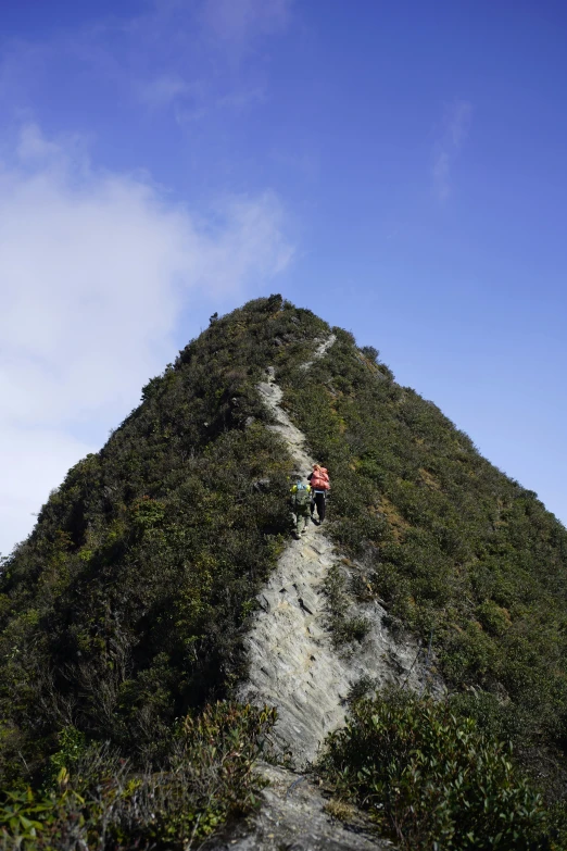 two people hiking up the side of a steep mountain