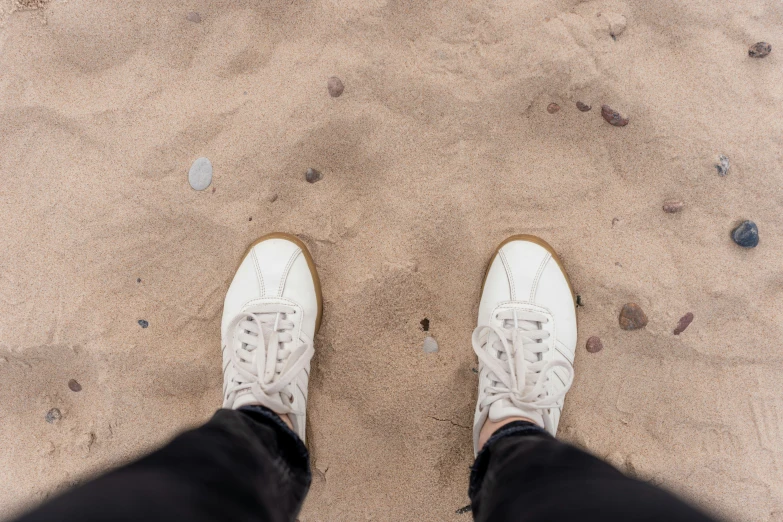 a person standing in sand with shoes on