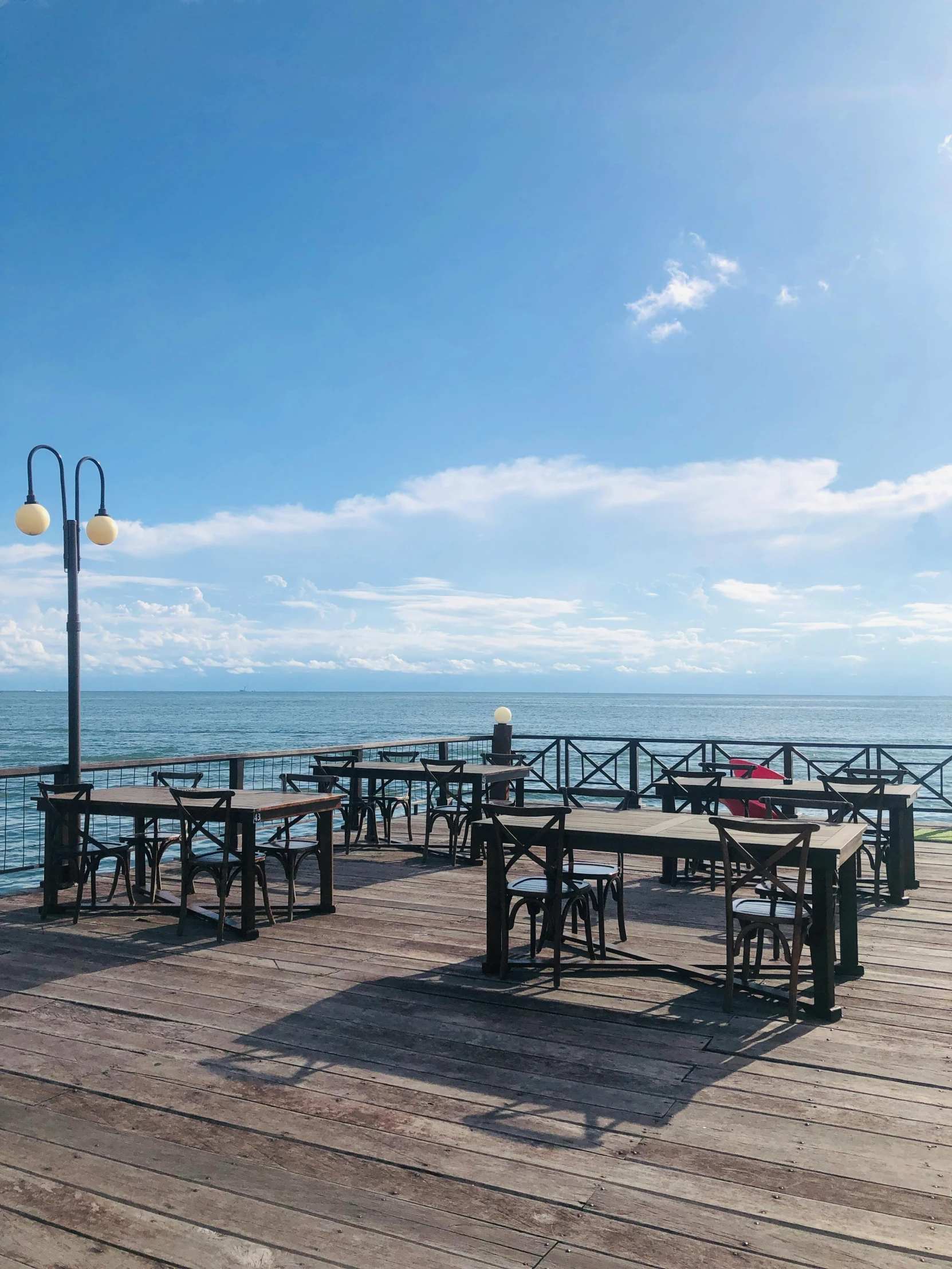 empty tables on the pier by the water