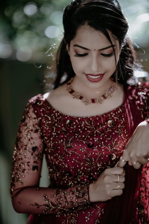 a woman in a red dress holding her wrist with both hands