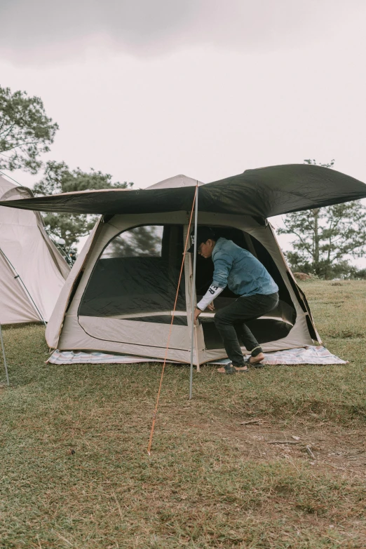 a man sitting inside of a tent with the door open