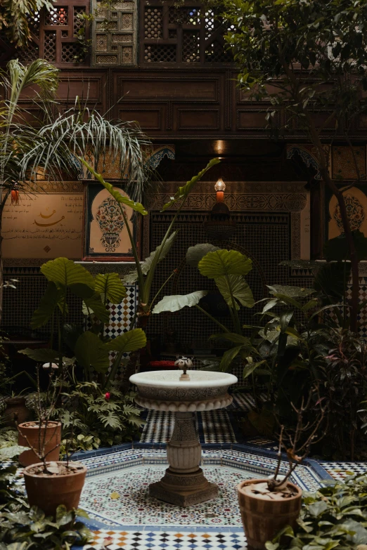 a fountain inside of a garden with a potted plant
