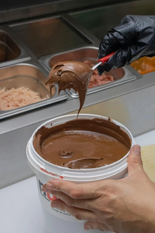 hands hold a jar and spread chocolate on it