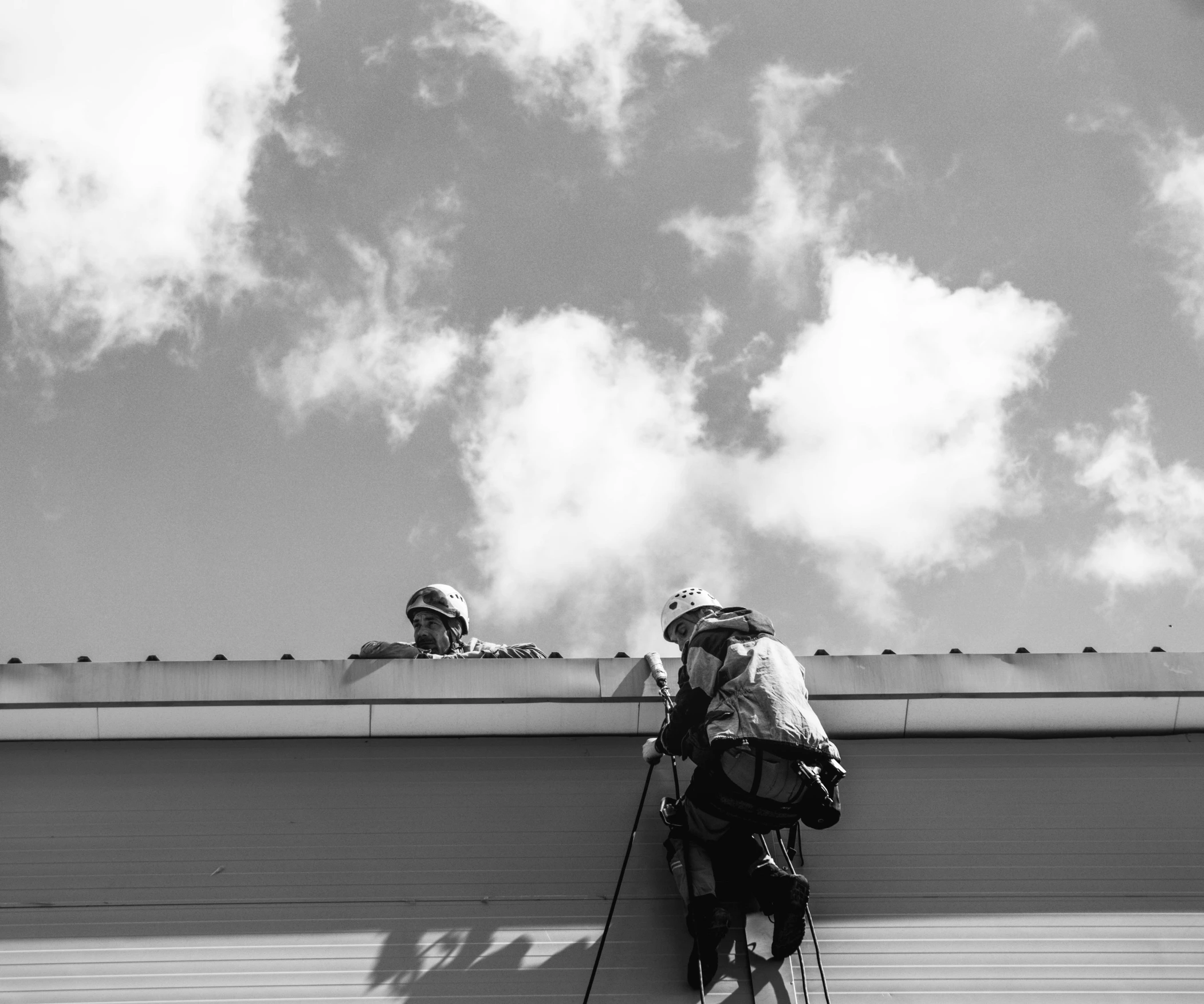 a man sitting on a roof next to a backpack and stick