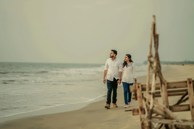 a man and woman walking on a beach holding hands