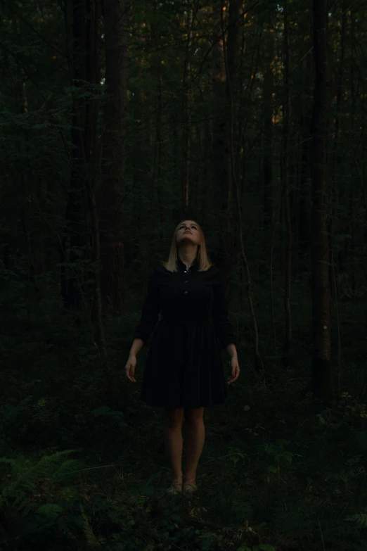 a woman in a dark forest wearing a black dress