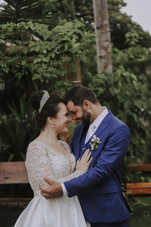 a bride and groom posing together in front of a wooden bench