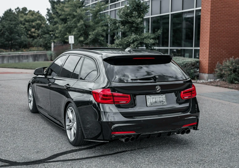 the rear end of a bmw sedan parked in front of a building