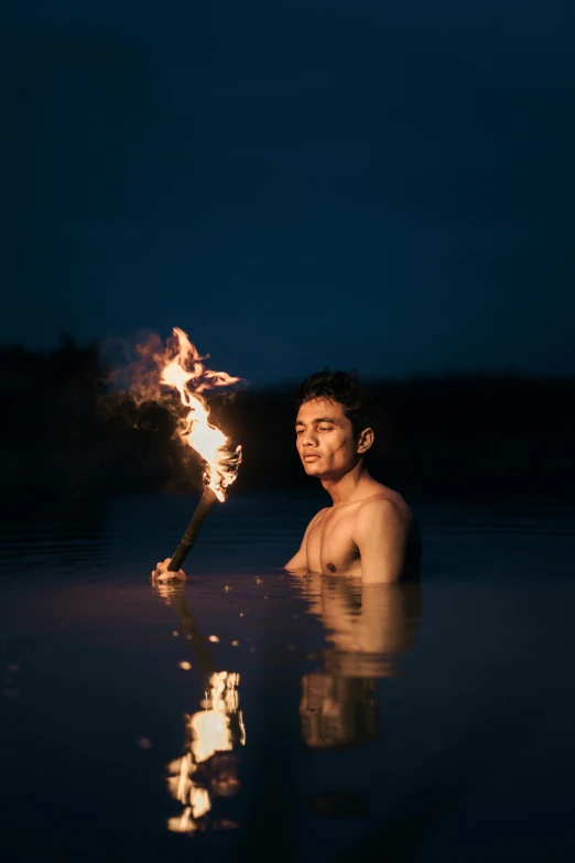 the man is holding a stick with flames in it