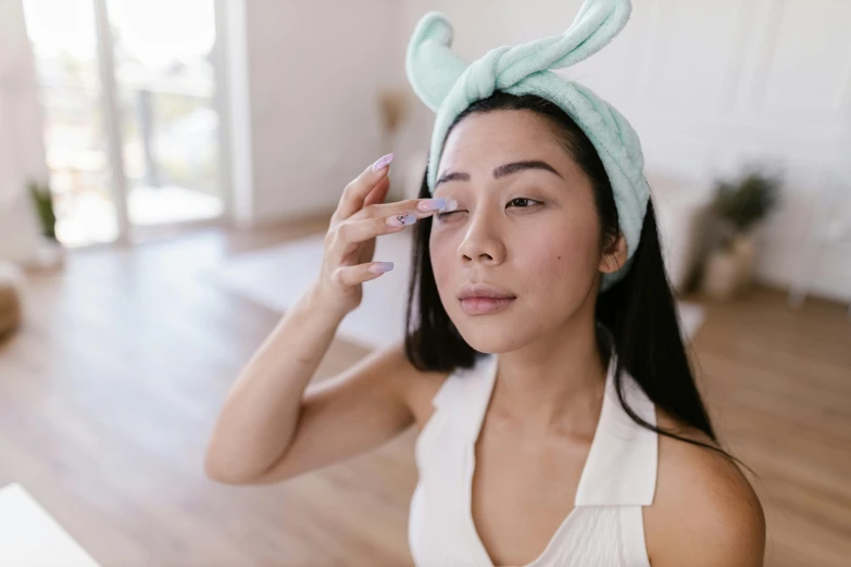 young woman with bunny ears putting on eye makeup