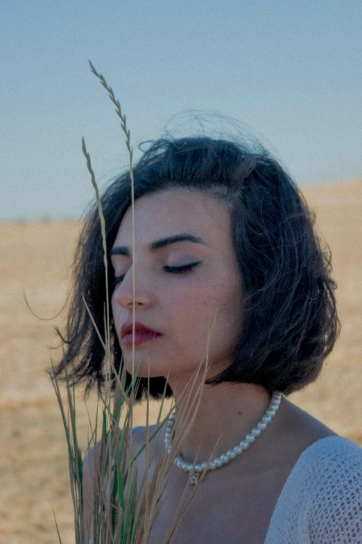 a woman standing in a field with a necklace on