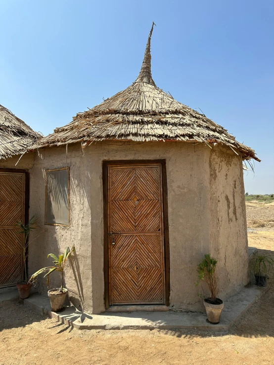 a small mud building with a thatch roof