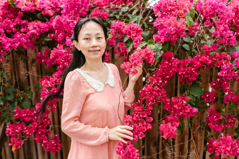 a young woman poses in front of a variety of pink flowers
