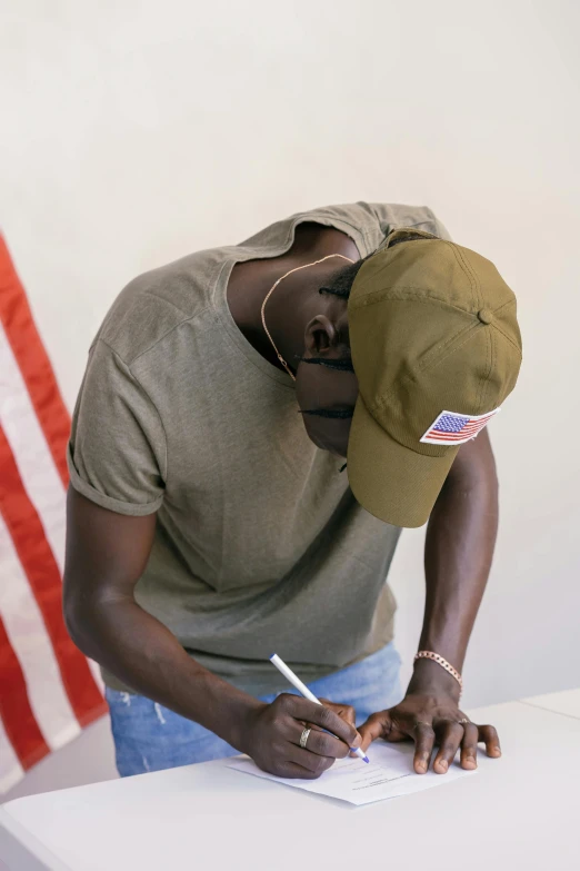 a man writing soing on a paper next to an american flag