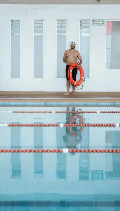 a man standing at the edge of a pool holding a life preserver