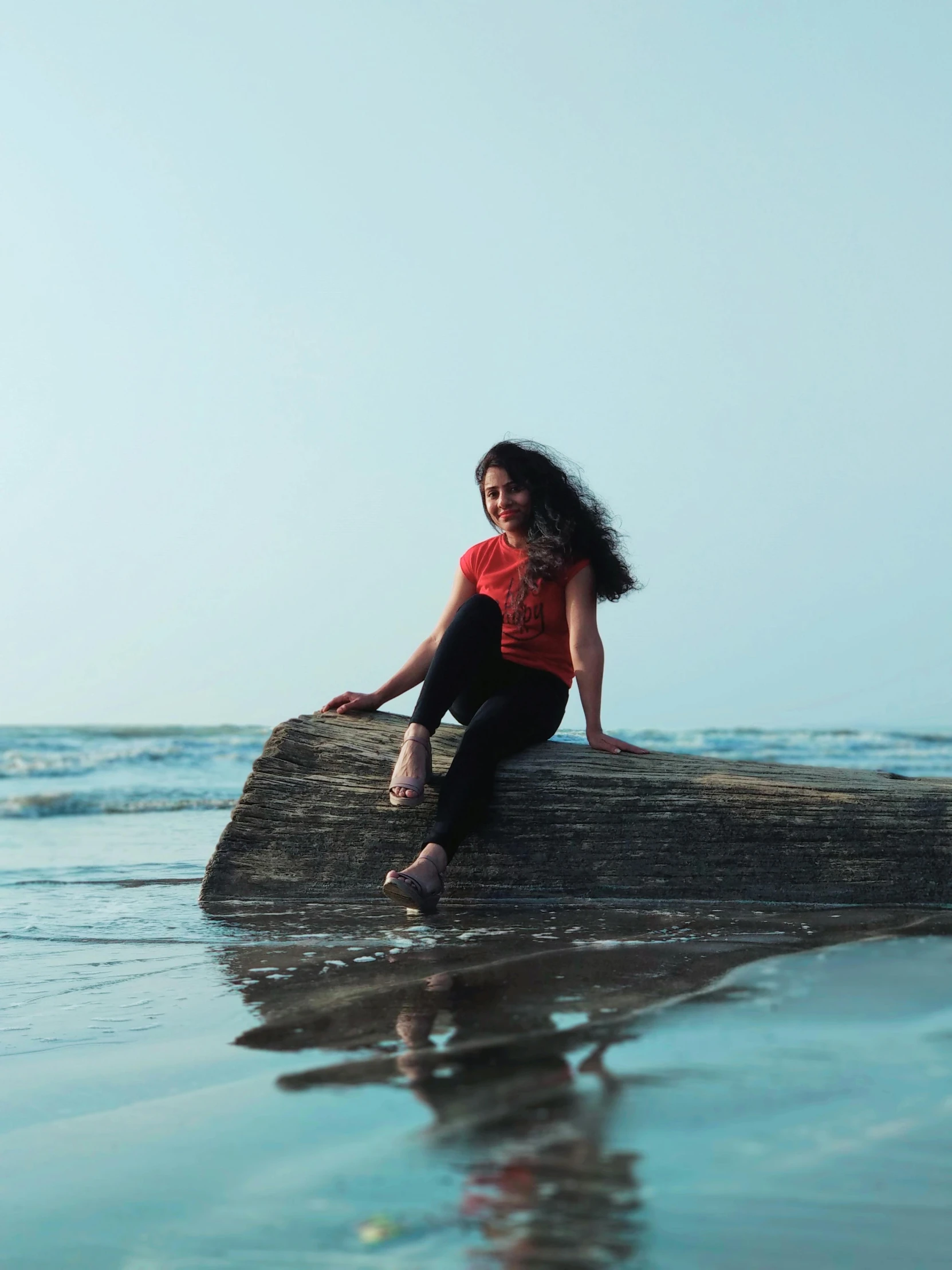 a woman sitting on a rock in the ocean