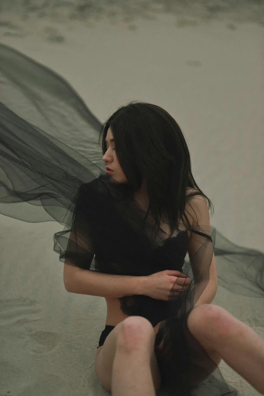 a woman with sheer black shirt sitting on concrete