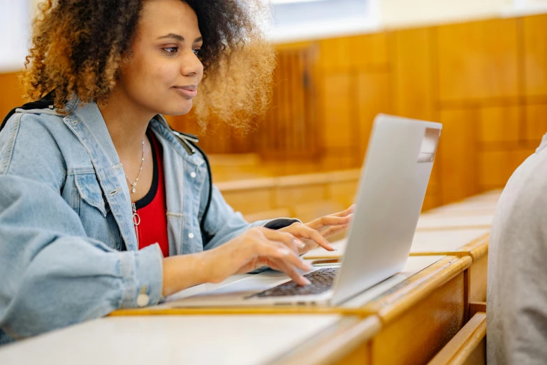 a woman sitting at a table in a court room working on her laptop