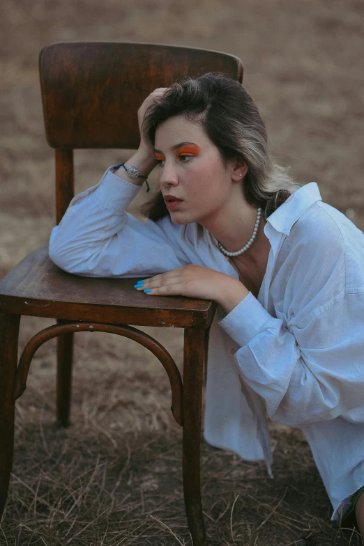 a woman sitting in a chair while she is holding her head to her side