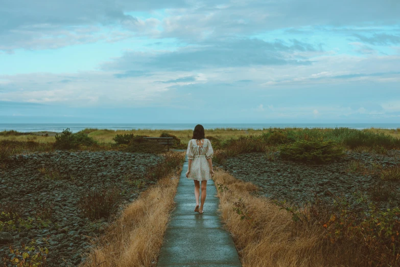 there is a woman standing on the end of a dirt path