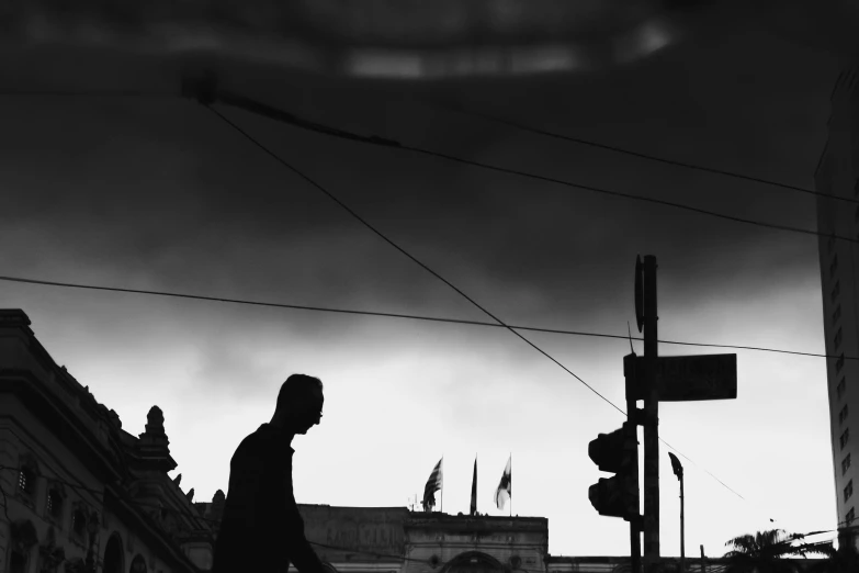 the silhouette of a man walking across the street