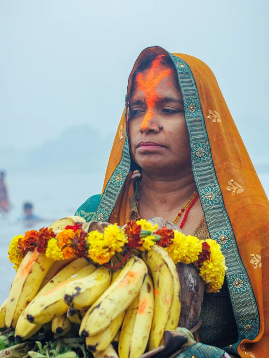 a woman holds bunches of bananas while a man in the background stands behind her