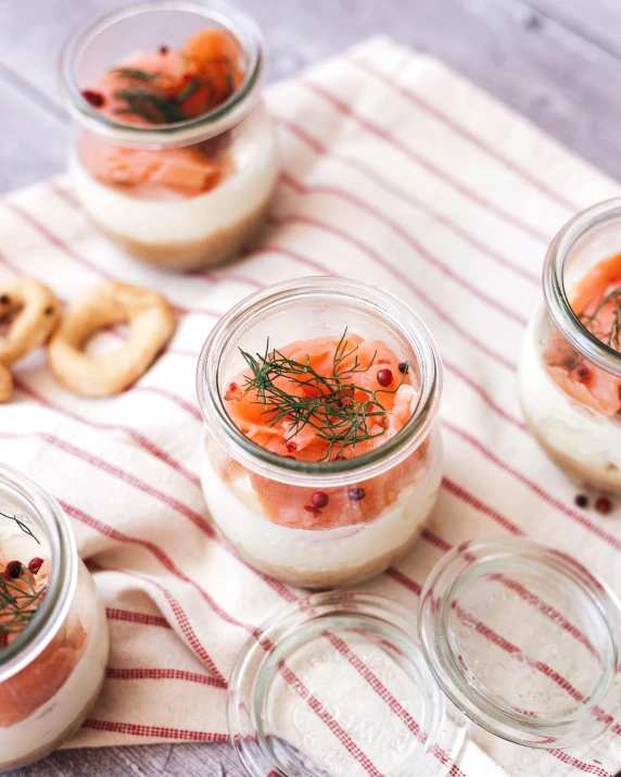 three jars with orange and purple toppings sit on a striped towel