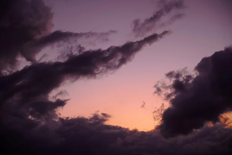 an airplane is flying high in the sky as a setting sun goes down