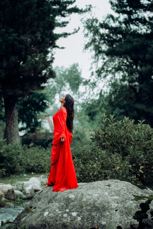 a woman in a red robe sitting on a rock