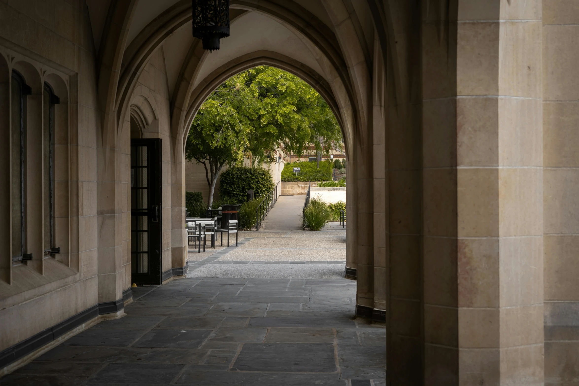 an arched building with a walkway and tables underneath it