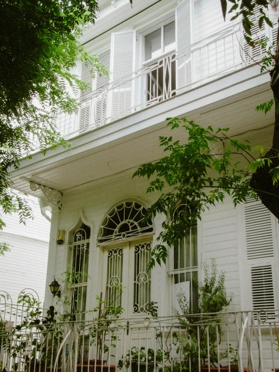 a white house with large windows next to a fence