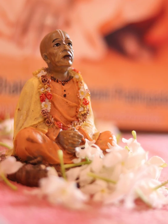 a small figurine sitting on top of a bed of flowers