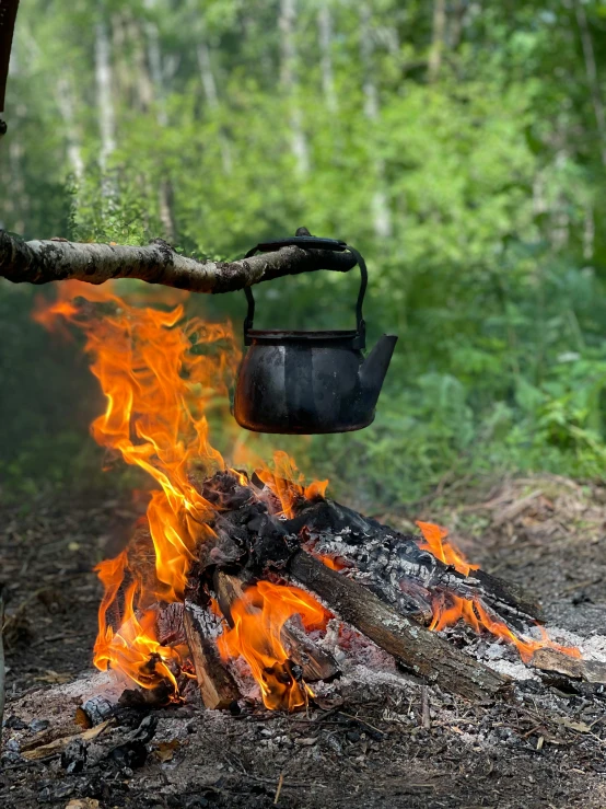 a large fire burning next to a pot on top of a stove