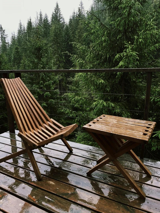 two wooden folding chairs on a deck overlooking a forest