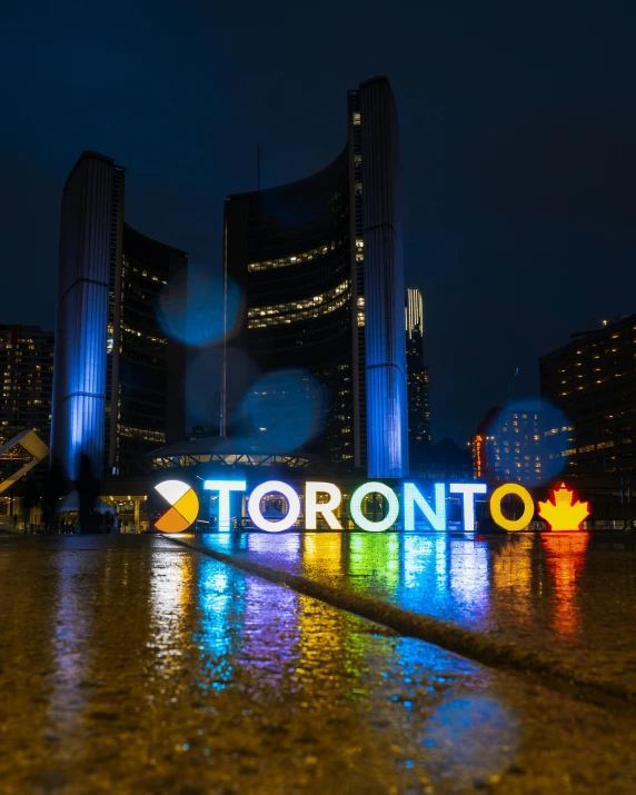 a toronto sign is illuminated on the road outside at night