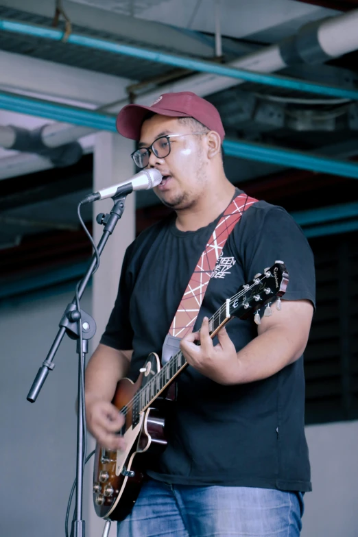 a man standing in front of a microphone and guitar