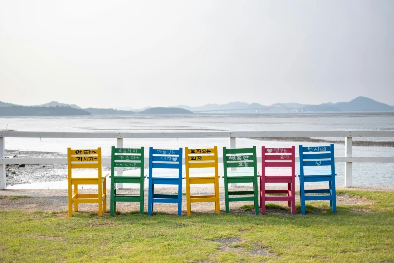 a row of colorful chairs sitting by the beach