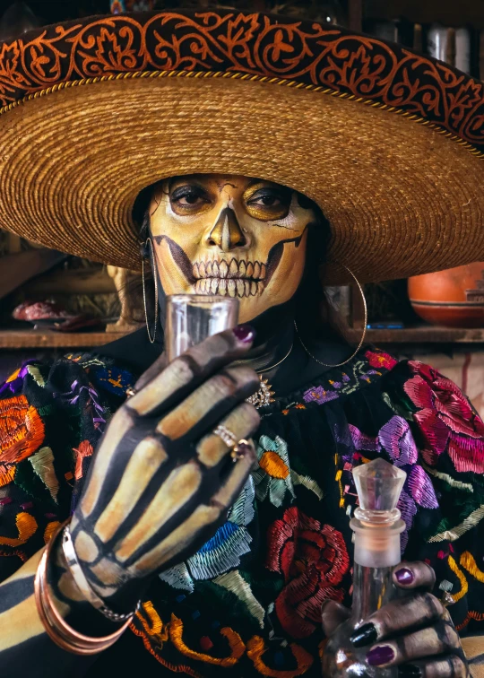 a man dressed in a sombrero holds a glass