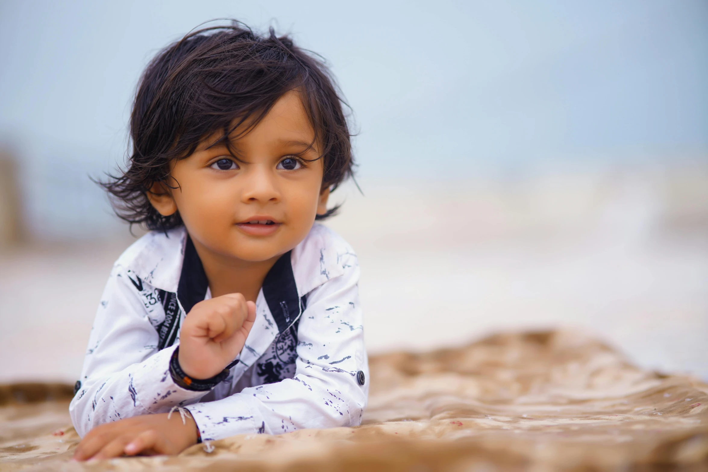 a little boy laying on his stomach looking up with hand in pocket